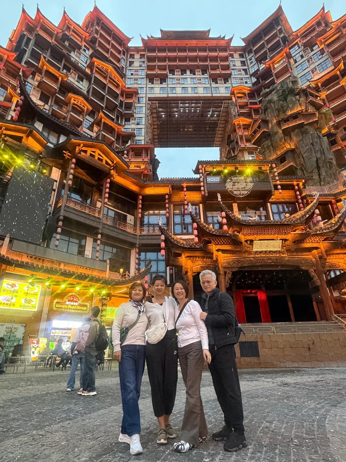 Group of travellers in front of a traditional Asian temple lit up at night